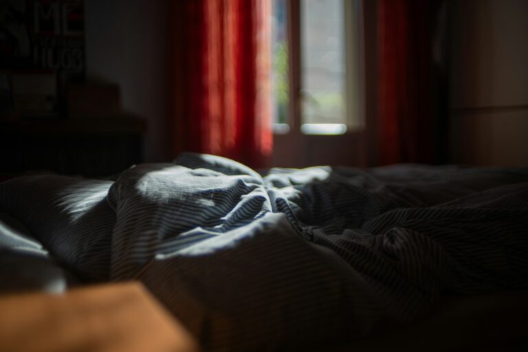 Quarto escuro com cama desfeita — sono profundo é onde a recuperação masculina realmente acontece
